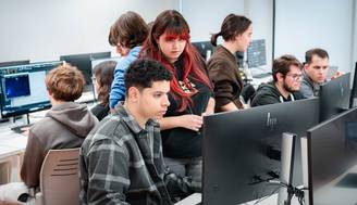 Un grupo de estudiantes trabaja en computadoras en un aula de informática.