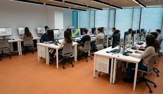 Un aula moderna con estudiantes trabajando en computadoras en estaciones de trabajo organizadas.