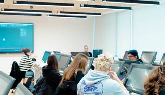 Una aula con estudiantes utilizando computadoras en un ambiente de aprendizaje.