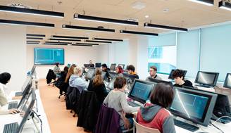Un aula moderna con estudiantes trabajando en computadoras.