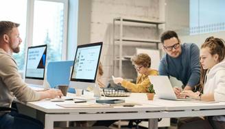 Un grupo de personas trabaja en un espacio de oficina moderno, concentrados en sus computadoras.