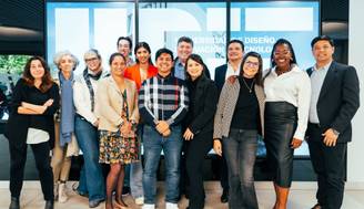 Grupo de personas posando juntas frente a una pantalla en un entorno académico.