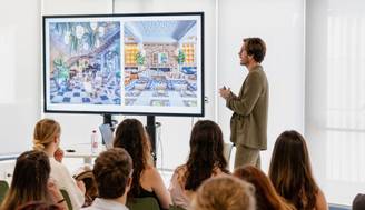 Un presentador está mostrando un diseño de interiores a un grupo de personas en un espacio moderno.