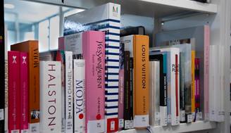 Una estantería con libros de moda destacados de diferentes diseñadores.
