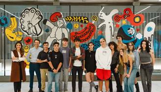 Un grupo de jóvenes posando frente a un mural colorido en un espacio interior moderno.