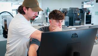 Dos personas trabajan juntas en una computadora en un entorno moderno de oficina.