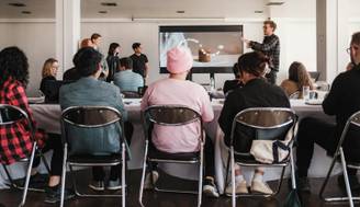 Un grupo de personas en una sala de conferencias escuchando una presentación en una pantalla.