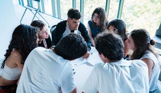 Un grupo de jóvenes está colaborando en un proyecto alrededor de una mesa.