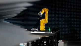Un robot industrial de color amarillo se encuentra en una sala con paredes de paneles acústicos.