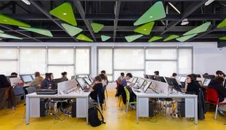 Una sala de computación donde estudiantes trabajan frente a escritorios con ordenadores.