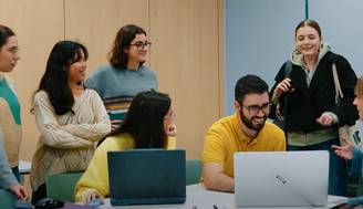 Un grupo de personas observa con interés la pantalla de un ordenador en un ambiente de aprendizaje.