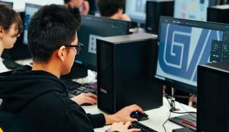 Un estudiante trabaja en una computadora en un aula de diseño gráfico.