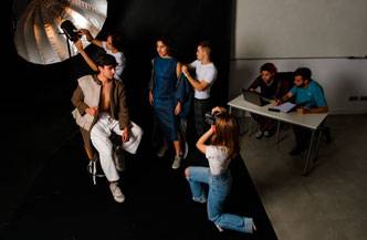 Una sesión de fotos en estudio donde varios modelos y un fotógrafo trabajan juntos.