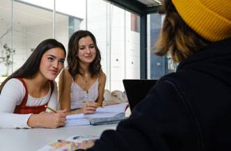 Dos jóvenes sonrientes conversan en un ambiente de estudio moderno.