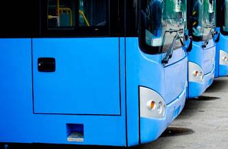 Un conjunto de autobuses de color azul aparcados en la calle.