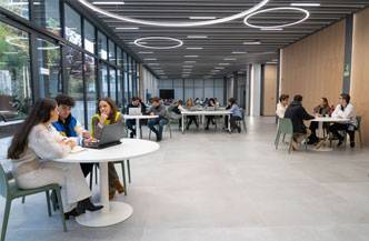 Un espacio moderno y luminoso donde diversas personas estudian y colaboran en mesas.