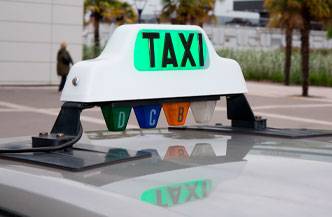 Un cartel de taxi iluminado en la parte superior de un vehículo.