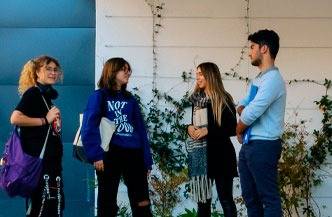 Cuatro jóvenes conversan en un entorno al aire libre rodeados de vegetación.