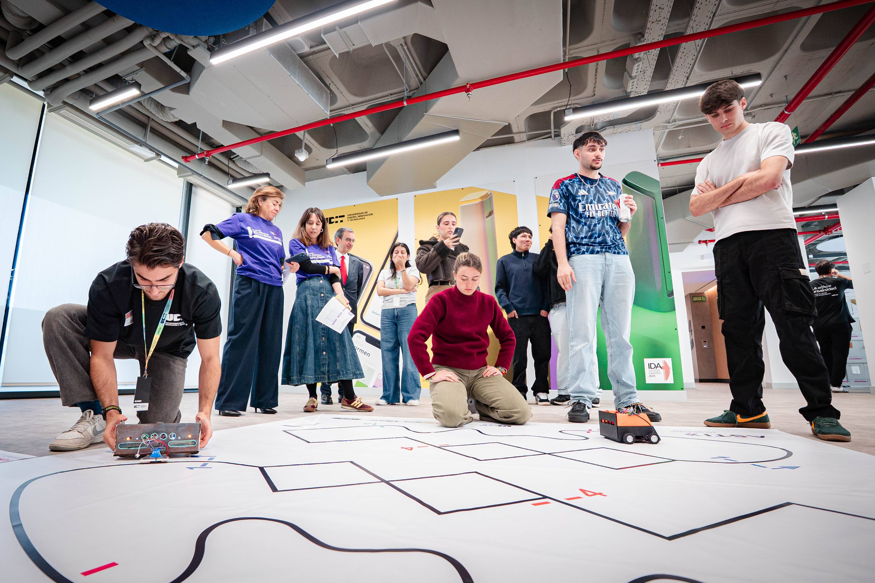 Un grupo de personas observa y participa en una actividad educativa relacionada con la programación de robots en un espacio moderno.
