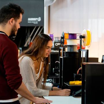 Dos personas trabajando con impresoras 3D en un laboratorio.