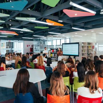 Un grupo de personas asiste a una presentación en un aula moderna y colorida.