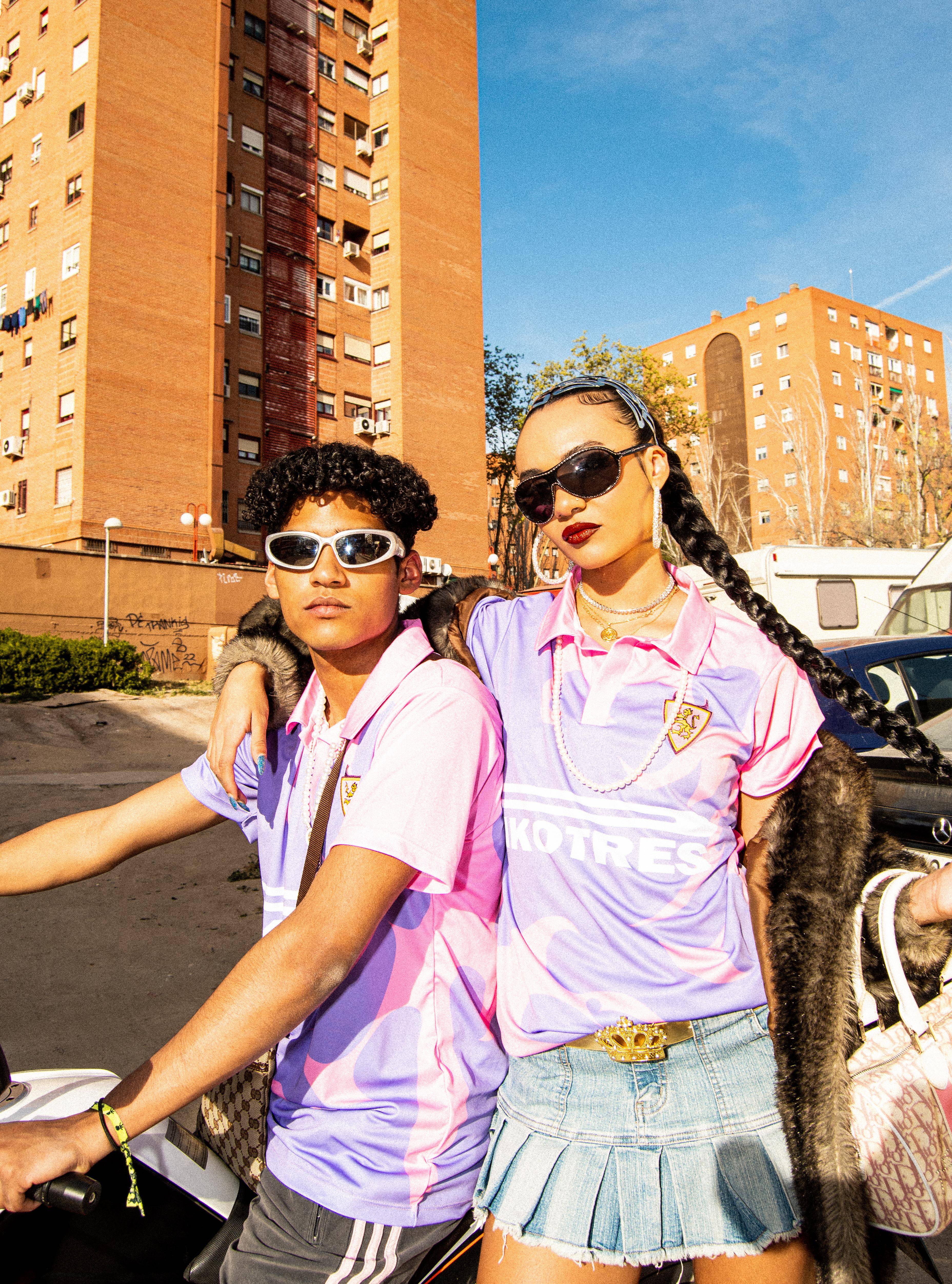 Una pareja de jóvenes con ropa colorida posando en un entorno urbano.