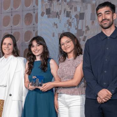 Un grupo de cuatro personas posando en un evento, donde una de ellas sostiene un premio.