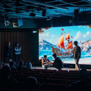 Una presentación en un auditorio con una gran pantalla que muestra un barco en el mar y personas interactuando en el primer plano.