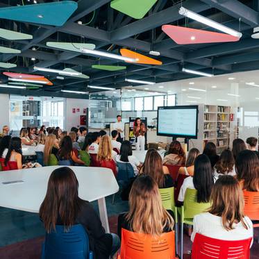 Un grupo de personas asiste a una presentación en una sala moderna y colorida.