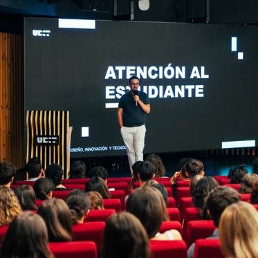 Un presentador habla ante un público durante un evento en un auditorio.