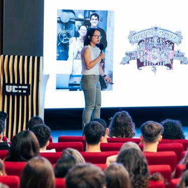 Una presentadora expone sobre 'Game Jams' frente a una audiencia en un salón de conferencias.