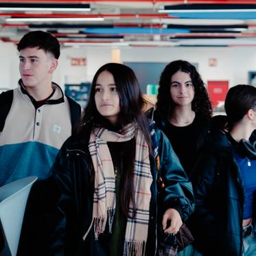 Un grupo de cuatro adolescentes camina por un espacio interior moderno y luminoso.