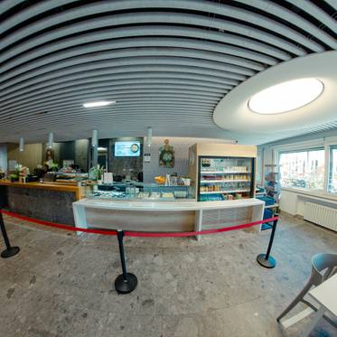 Un café moderno con una barra de atención y mesas en un ambiente luminoso.