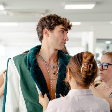 Un grupo de personas ayuda a un modelo a probarse una prenda de vestir en un taller de moda.