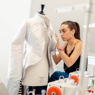 Una diseñadora de moda trabaja en una prenda utilizando una máquina de coser en su estudio.