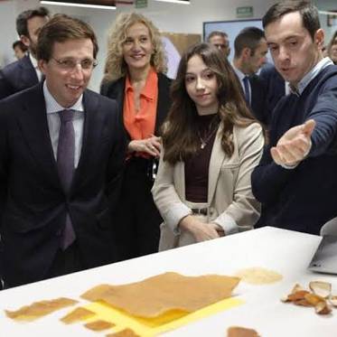 Un grupo de personas observa atentamente una demostración de productos sobre una mesa en un entorno de oficina moderna.