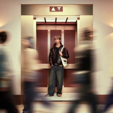 Un joven espera en un ascensor mientras las personas pasan rápidamente a su alrededor.