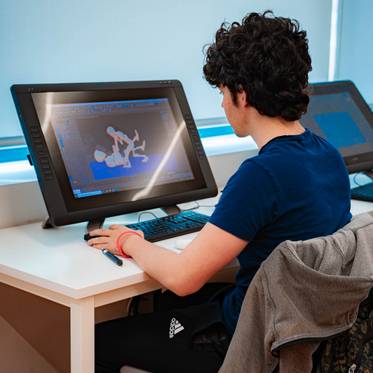 Un joven trabaja en una computadora gráfica en un entorno iluminado.