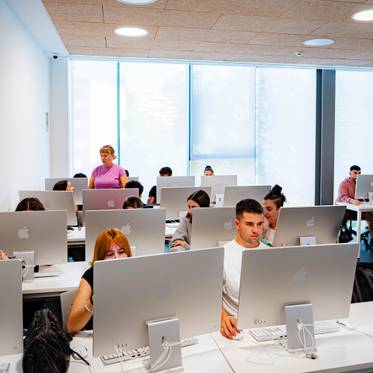 Un grupo de estudiantes trabaja en sus ordenadores en un aula moderna.