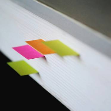 Una imagen que muestra un libro con varios marcadores de colores brillantes sobresaliendo de su parte superior.
