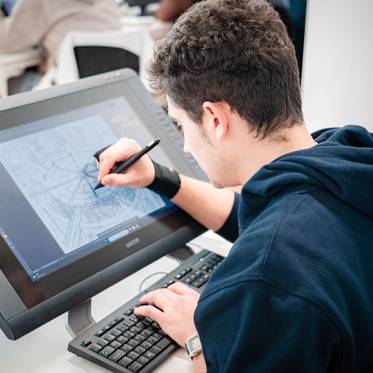 Un joven está dibujando en una tableta gráfica mientras trabaja en un entorno de oficina.