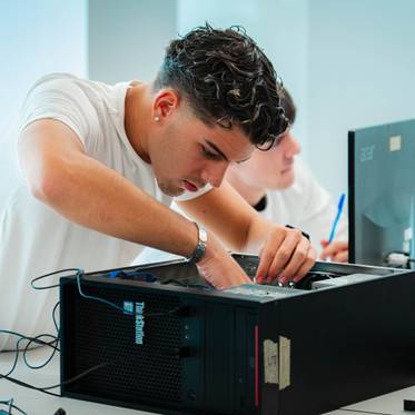 Un joven está reparando un computador en un ambiente de aprendizaje.