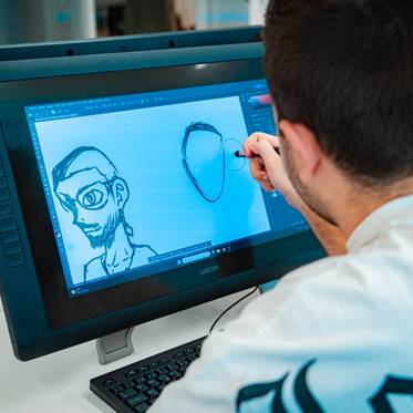 Una persona está dibujando en una tablet digital con un diseño de un rostro en la pantalla.