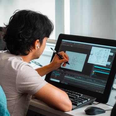 Un joven dibujante trabaja en su mesa con una pantalla digital.