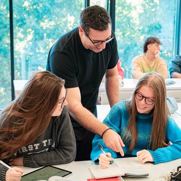 Un profesor enseña a dos estudiantes en un aula moderna.