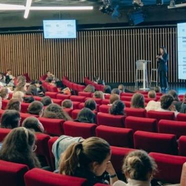 Una conferencia con una gran audiencia sentada en un auditorio moderno.