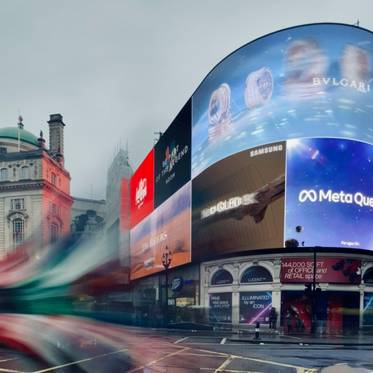 Una vista de Piccadilly Circus con pantallas publicitarias brillantes en un día nublado.