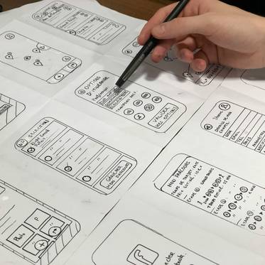 Un boceto en papel de varias pantallas de una aplicación móvil que está siendo diseñado.