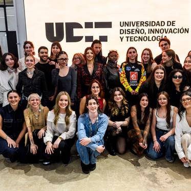 Grupo de estudiantes posando frente al logo de la Universidad de Diseño, Innovación y Tecnología.