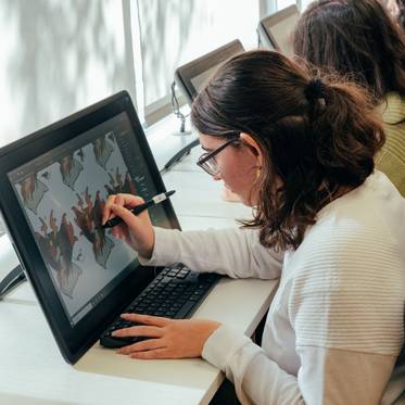 Una joven dibuja en una tableta digital en un entorno de trabajo moderno.